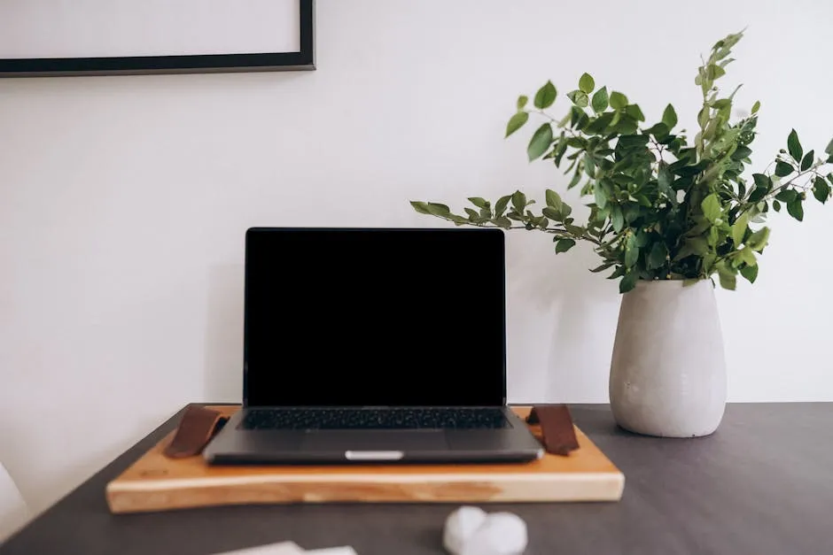 A modern home workspace featuring a laptop and a vase of green plants. — Photo by PNW Production on Pexels