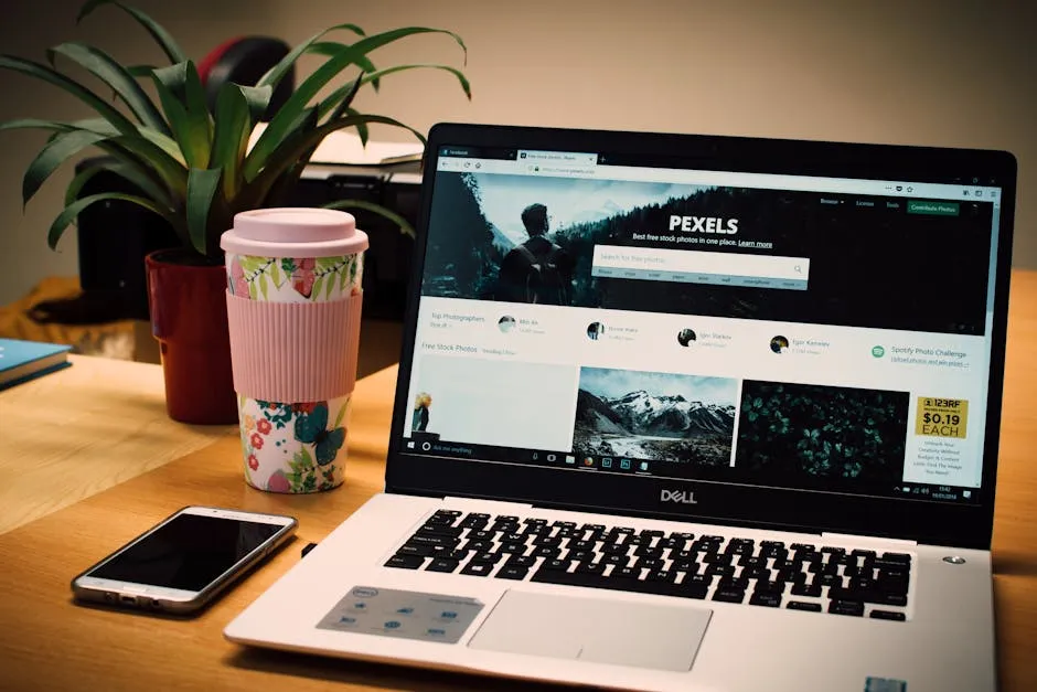 A tidy desk setting with a laptop showing a stock photo website and a smartphone. — Photo by Lisa from Pexels on Pexels