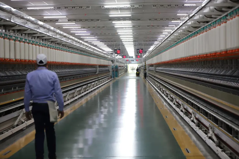 Long hallway in a textile factory with a worker walking, showcasing industrial machinery. — Photo by RAJESH KUMAR VERMA on Pexels